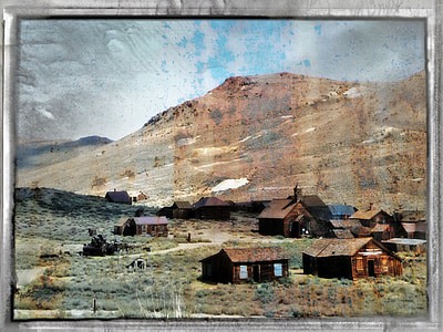 rectangular gray framed painting of brown houses near brown mountain thumbnail