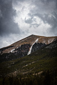 low-angle photo of mountains under thick gray clouds thumbnail
