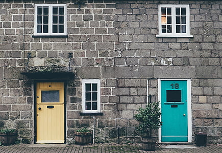 cinder block house with beige and teal doors thumbnail