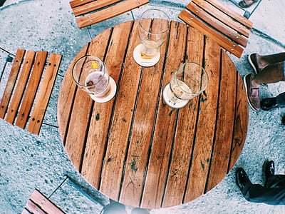 three clear glass beer pints on brown wooden table with chairs thumbnail