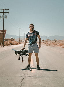 man carrying video camera standing on road thumbnail
