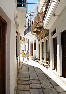 two women carrying bags walking between concrete houses thumbnail