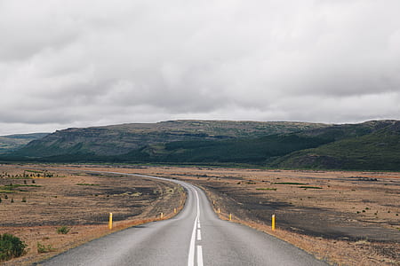asphalt road near hill under white cloudy skies thumbnail