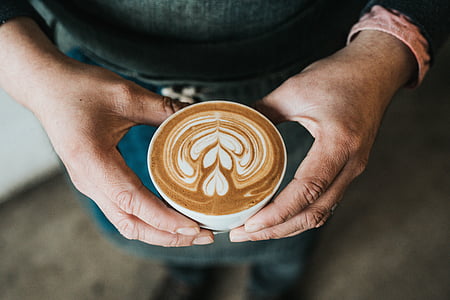 person holding mug filled with cafe latte thumbnail