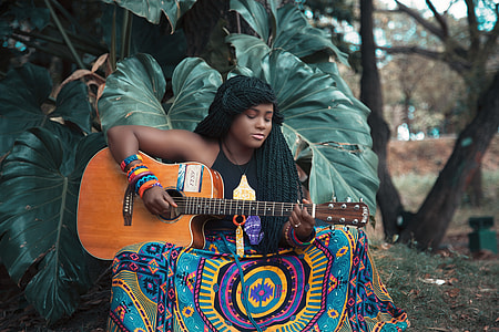 woman sitting under tree while playing acoustic guitar thumbnail