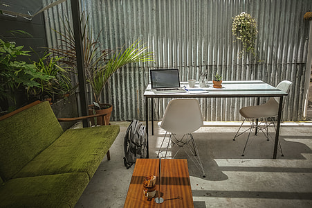 MacBook Pro on white table beside green padded sofa thumbnail