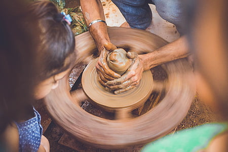 person making clay pot during daytime thumbnail