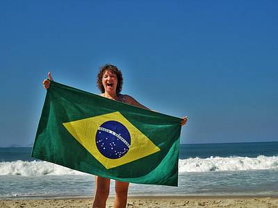 woman standing near body of water holding flag during daytime thumbnail
