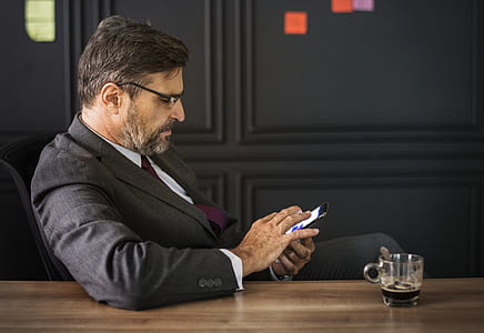 photo of man sitting on black chair using smartphone thumbnail