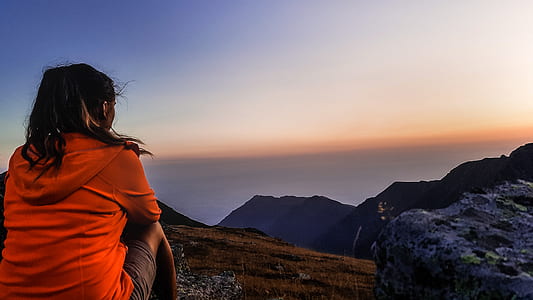woman sitting on elevated ground overlooking mountains during daytime thumbnail