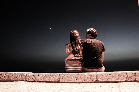 man and woman sitting on gray concrete pavement during night thumbnail