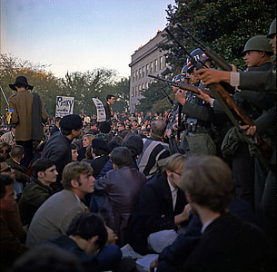 army holding rifle in front of people protesting during daytime thumbnail