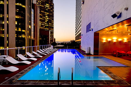 photo of swimming pool surrounded by white outdoor lounges thumbnail