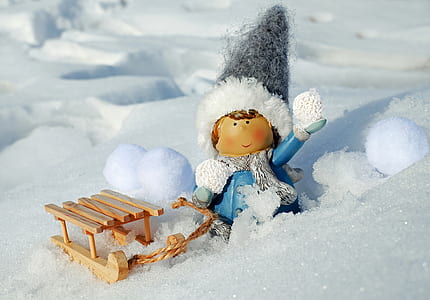 gray and blue dressed doll with sled on snow thumbnail