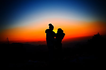 silhouette of man and woman overlooking sunset thumbnail