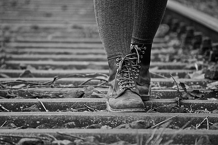 gray scale photography of person walking on train rail thumbnail