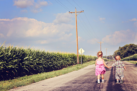 boy and girl holding hands while walking along the road thumbnail