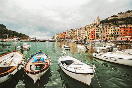 several wooden boats on body of water near multicolored concrete buildings thumbnail