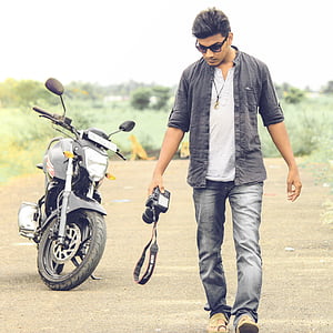man walking beside black motorcycle thumbnail