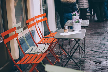 four orange and white folding chairs in front of two square gray tables thumbnail