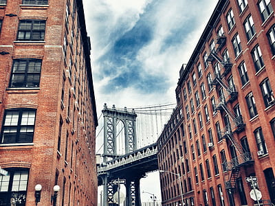 gray bridge between brown concrete buildings during daytime thumbnail