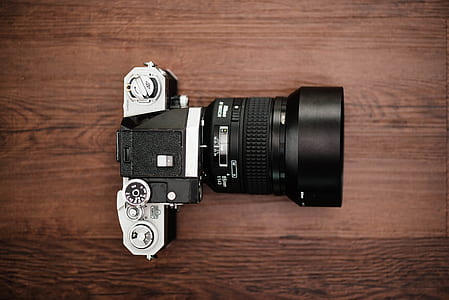 black and silver DSLR camera on top of brown wooden table thumbnail