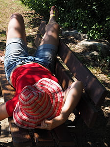 woman lying on brown wooden bench during daytime thumbnail
