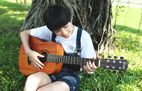 woman playing guitar under tree thumbnail
