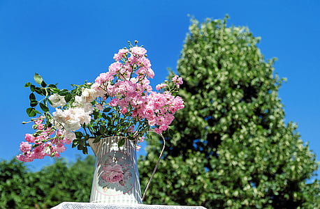 close-up photography of pink and white petaled flowers in white ceramic vase during daytime thumbnail