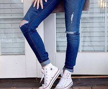 woman wearing distressed whiskered blue jeans and white Converse All-Star high-top sneakers thumbnail