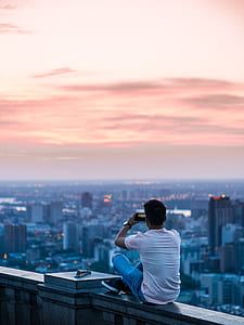 man sitting on gray concrete edge during sunset thumbnail