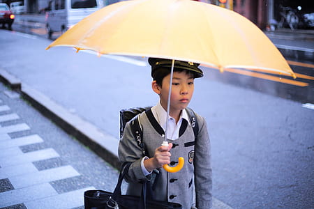boy wearing school uniform holding a yellow umbrella thumbnail