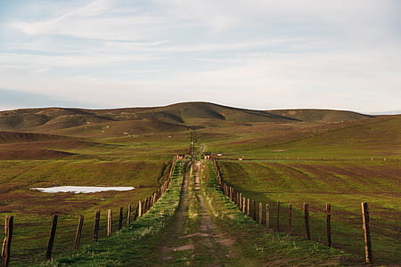 walkway between brown wooden fence with mountains at daytime thumbnail