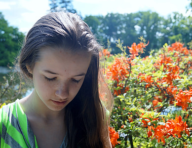 girl near flowers closing her eyes during daytime thumbnail