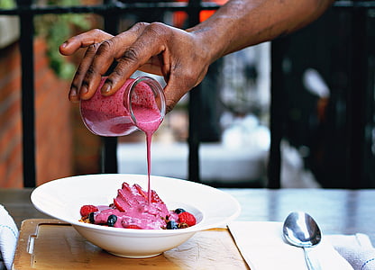 person pouring strawberry syrup on mixed berry fruit thumbnail