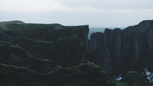 person standing on green and gray mountain thumbnail