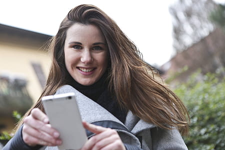Woman in Gray Coat Holding White Smartphone thumbnail