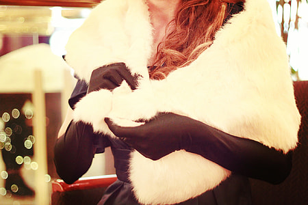 woman wearing black gloves holding white fur scarf inside well lighted room thumbnail
