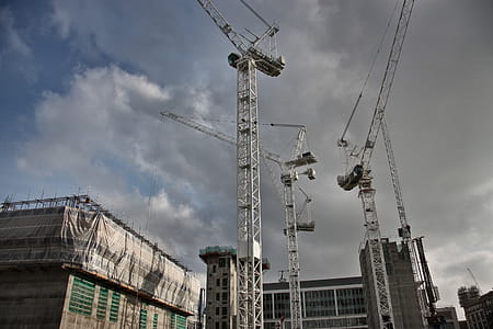 View of Cranes working on a construction site, with dark clouds seen in the sky thumbnail