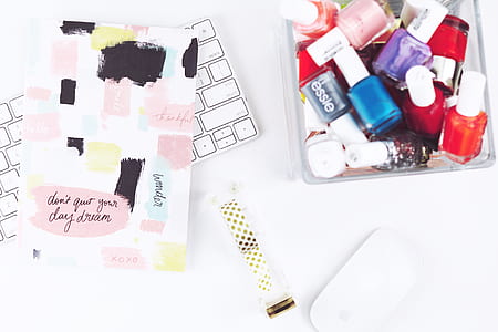 top view of assorted-color nail polish bottles beside book and wireless keyboard thumbnail