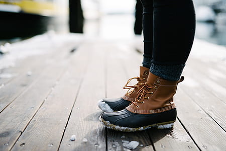 person in bean boots standing on brown wooden floor thumbnail
