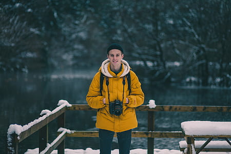 man holding DSLR camera near body of water thumbnail