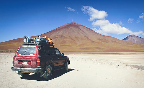 red SUV on desert in distant of mountain thumbnail