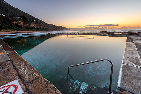 pool with warning sign near mountain thumbnail