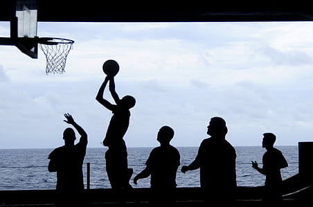 silhouette of people playing basketball near body of water thumbnail