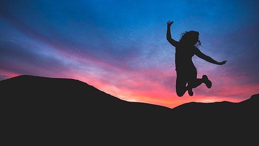 silhouette of woman jumping near mountain at sunset thumbnail