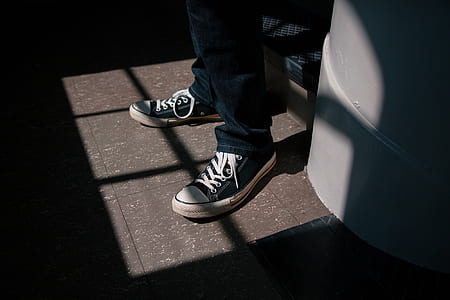person wearing black-and-white Converse All-Star sneakers behind white wall thumbnail