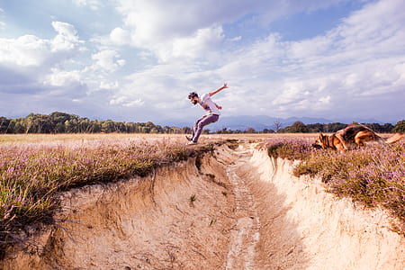 adult tan and black German shepherd and man with white t-shirt jumping on canal during daytime thumbnail