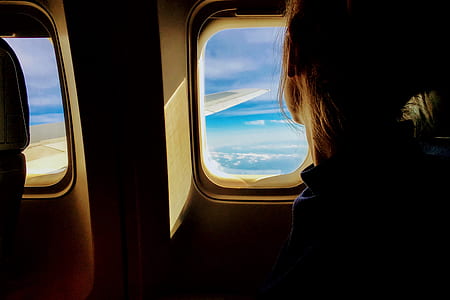 person sitting inside plane while looking on window during daytime thumbnail