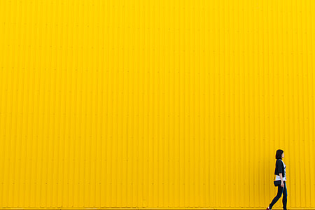 woman walking beside yellow wall thumbnail